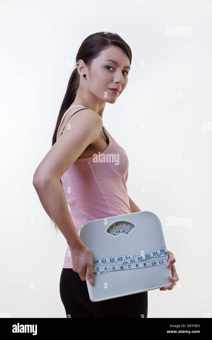 attractive woman holding scales with a tape measure wrapped around them Stock Photo Alamy