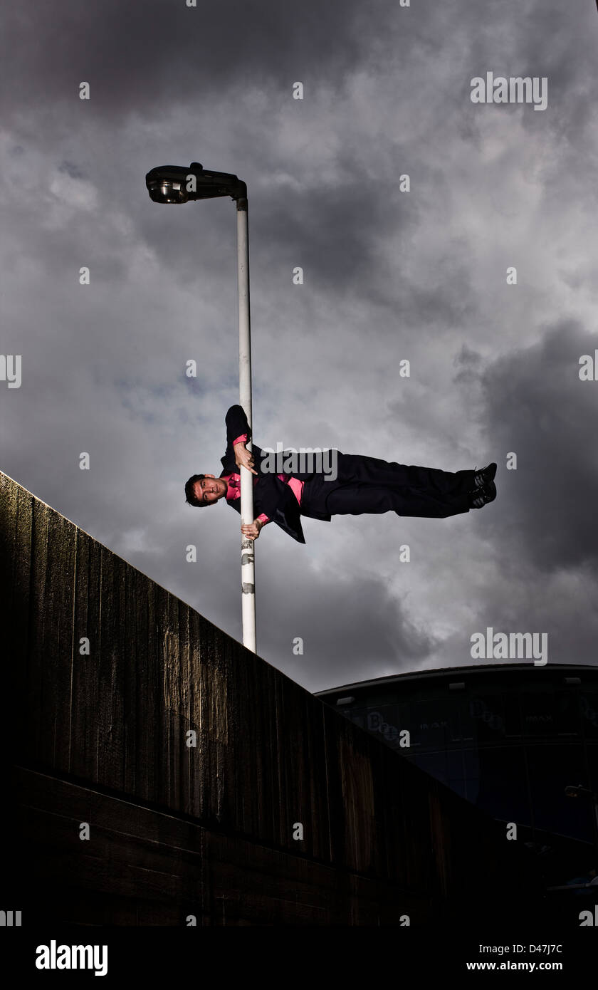 Parkour runner in suit balancing on lamppost Stock Photo