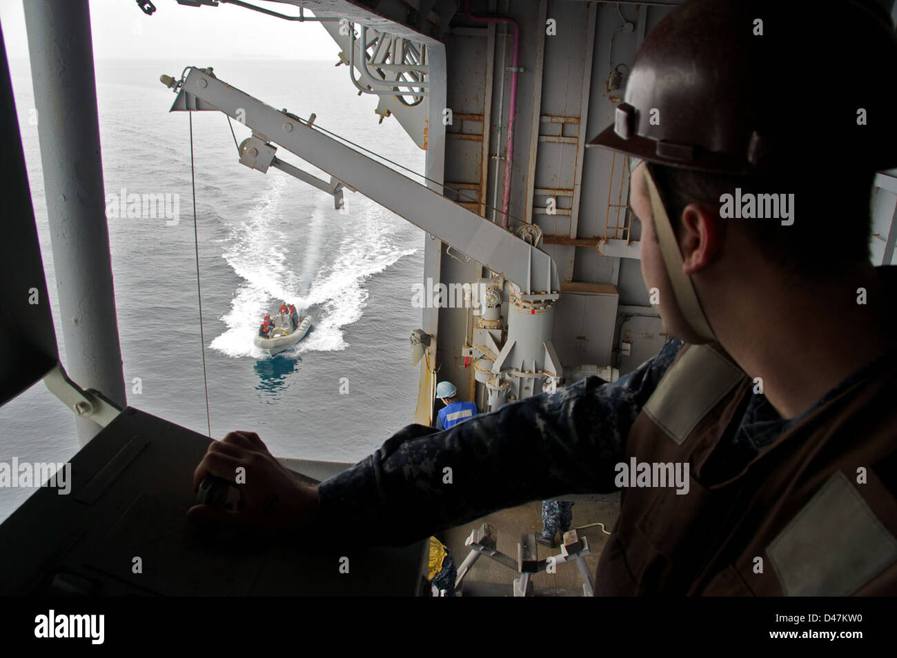 Sailors aboard a U.S. Navy ship retrieve a search and rescue boat ...