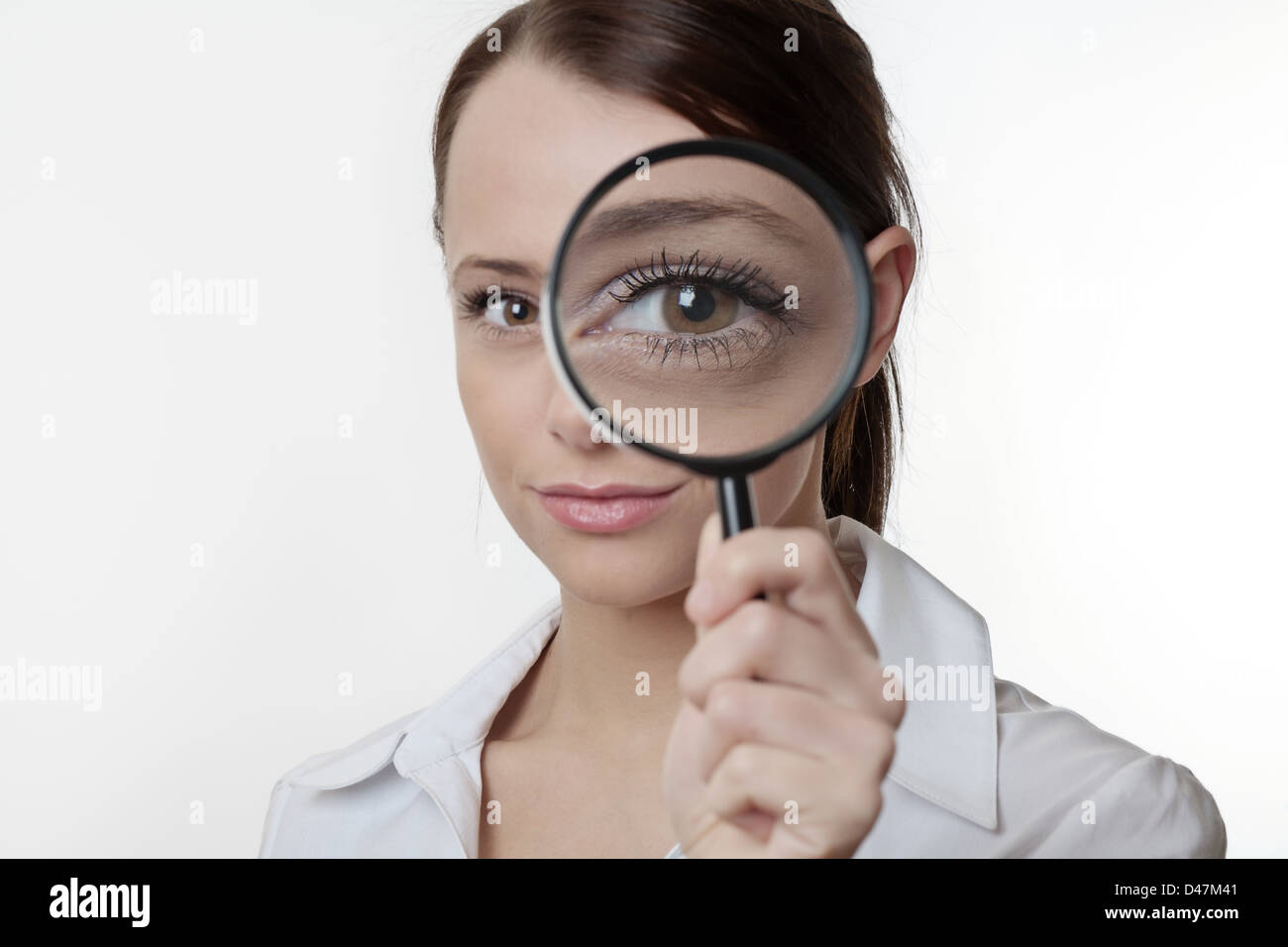 Confident young woman looking through a magnifying glass Stock Photo ...