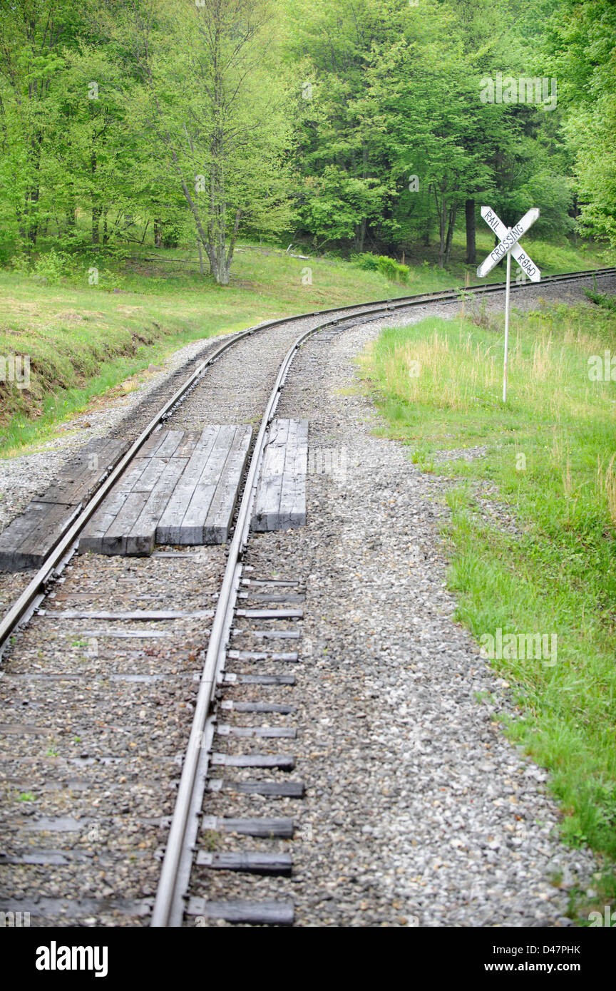 Railroad crossing in rural setting with one track in green summer landscape. Stock Photo
