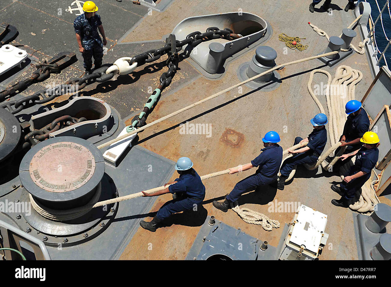 Sailors heave mooring lines around a capstan Stock Photo Alamy