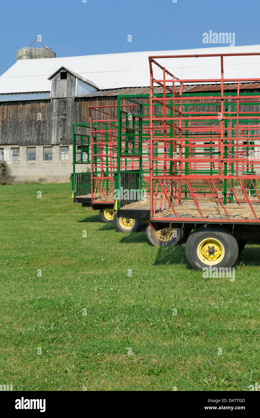 Hay wagons in a row, with a barn in the background, during bright  sunlight in the summer, agriculture in Pennsylvania, PA, USA. Stock Photo