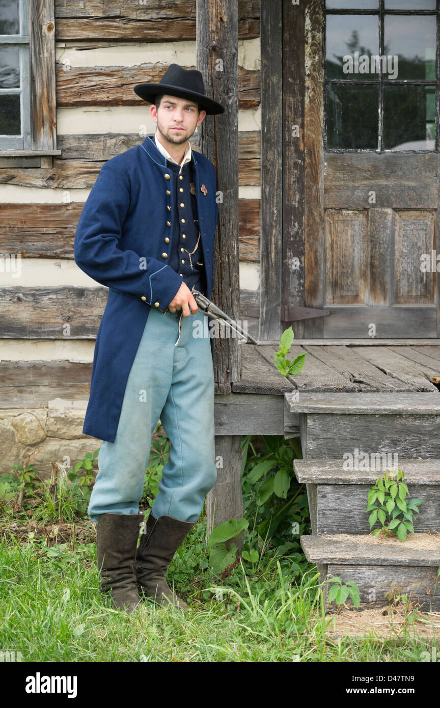 Soldier standing and posing with pistol, American Civil War Union infantry private by period log house. Stock Photo