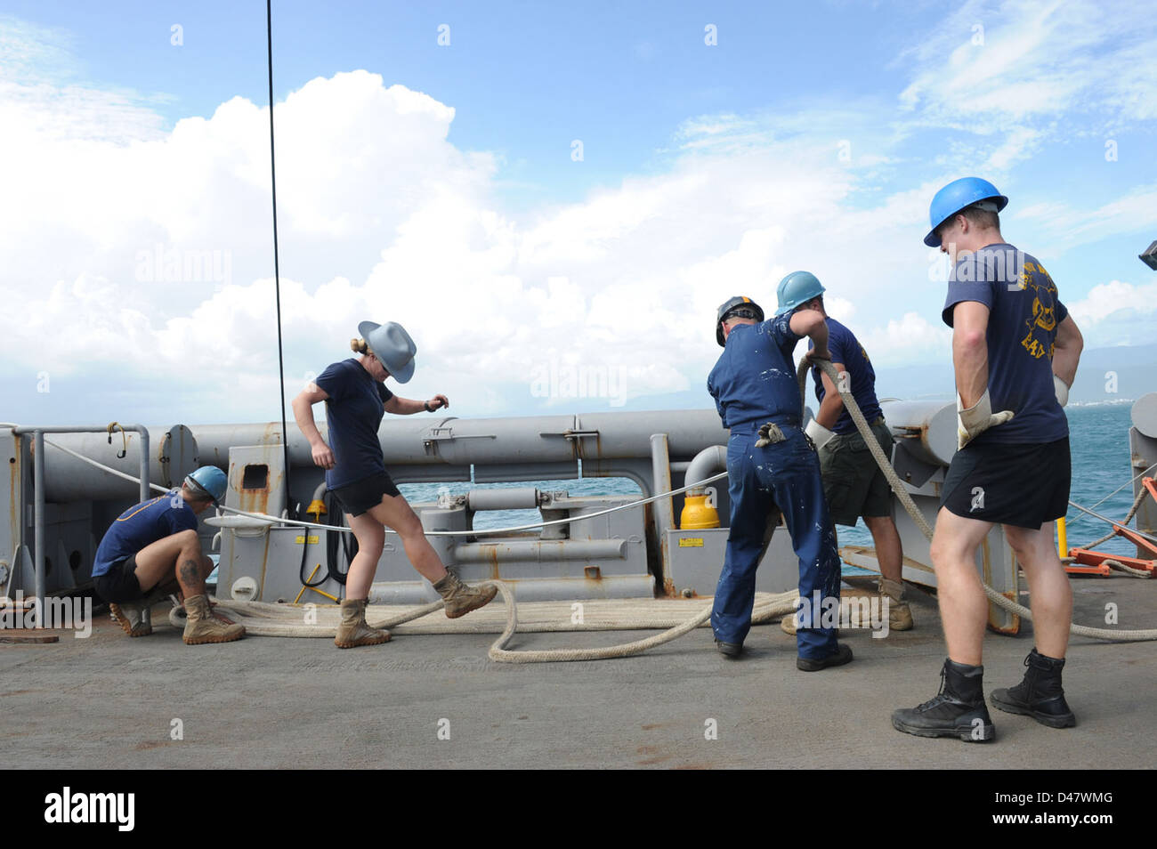 Sailors flake out a mooring line aboard USNS Grapple. Stock Photo
