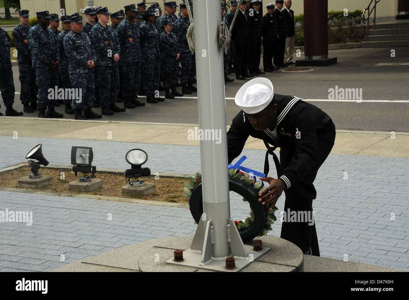 A Sailor places a wreath, made of red, white and blue flowers, at the ...