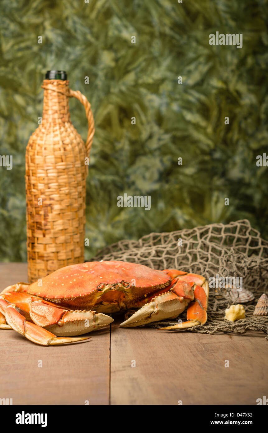 A Dungeness crab with net and wine bottle Stock Photo