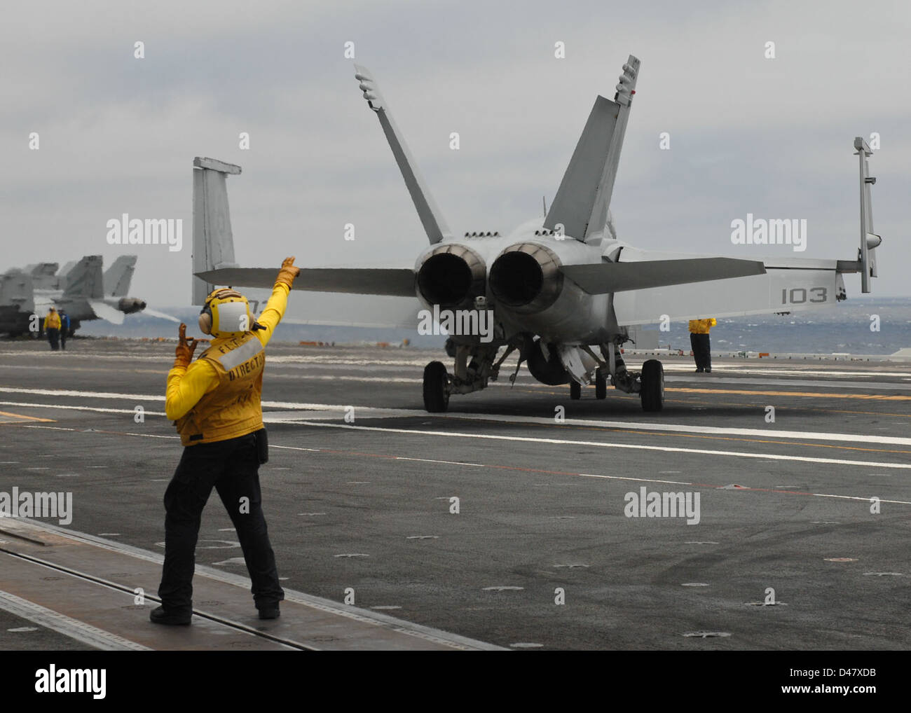 Sailors direct a jet on the flight deck. Stock Photo
