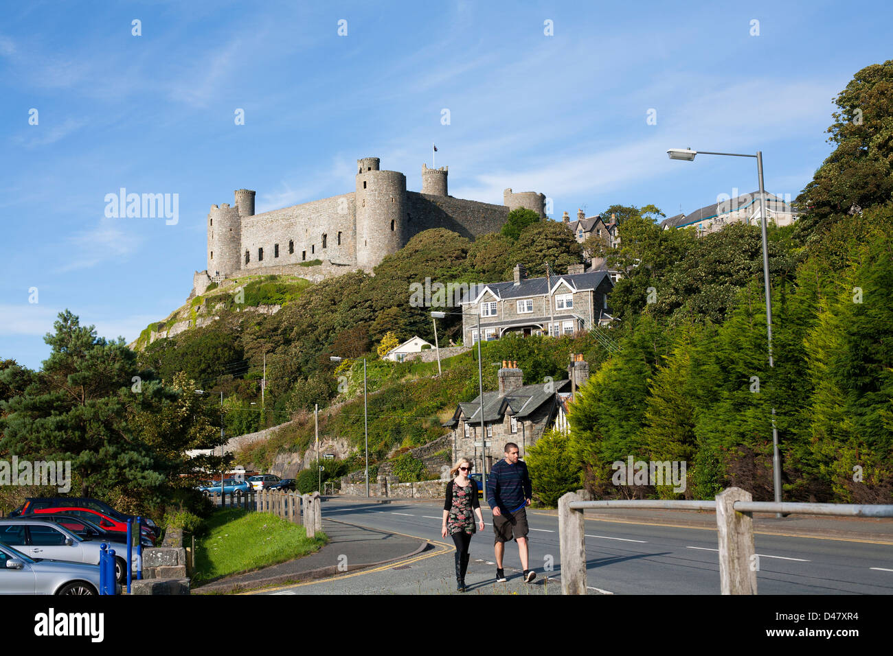 Two tourists walk past a historic Welsh Castle in North Wales on a sunny day Stock Photo