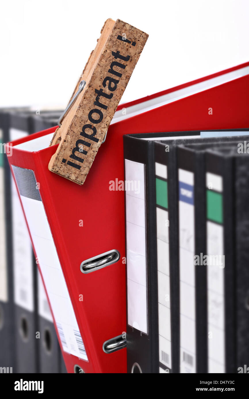 A red foldeer in a row of black ones. Stock Photo