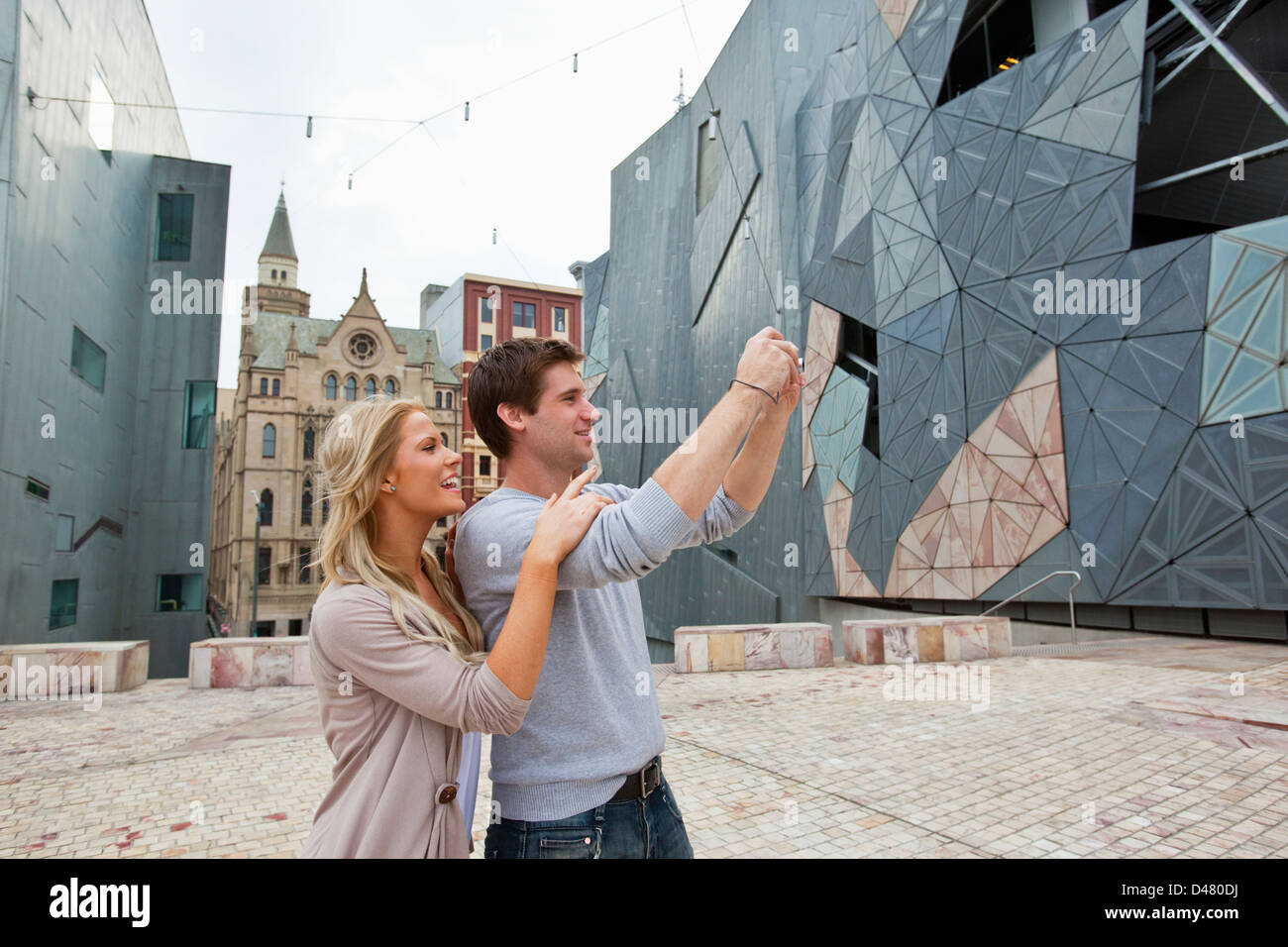 Young couple sightseeing in city, taking a picture. Federation Square, Melbourne, Victoria, Australia Stock Photo