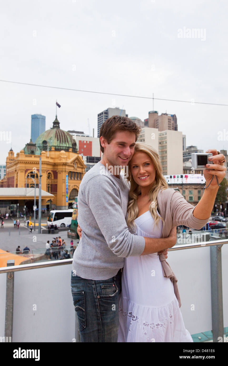 Young couple sightseeing in city, taking a self-portrait. Federation Square, Melbourne, Victoria, Australia Stock Photo