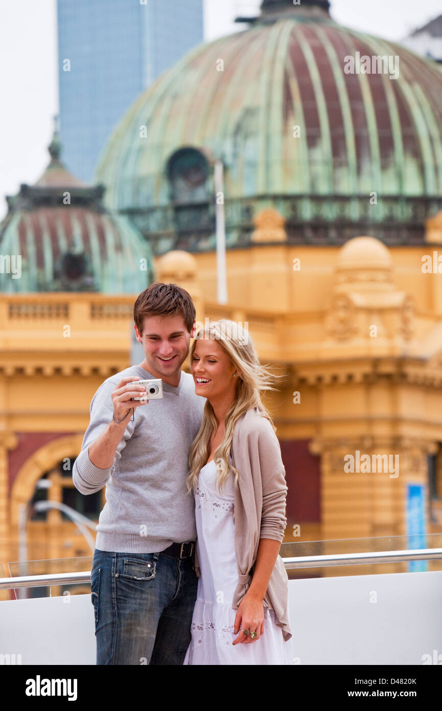 Young couple sightseeing in city, looking at pictures on camera. Federation Square, Melbourne, Victoria, Australia Stock Photo