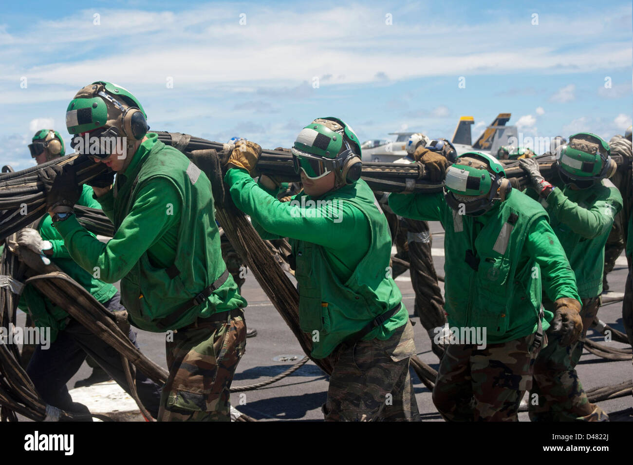 Sailors aboard a U.S. Navy vessel carry webbing during routine ...