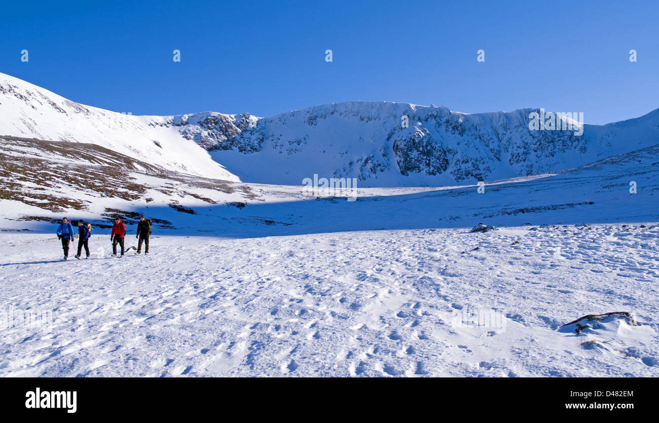 Four hillwalkers crossing snowfield below Coire an t-Sneachda, Northern Corries, Cairngorms National Park, winter, Scotland UK Stock Photo