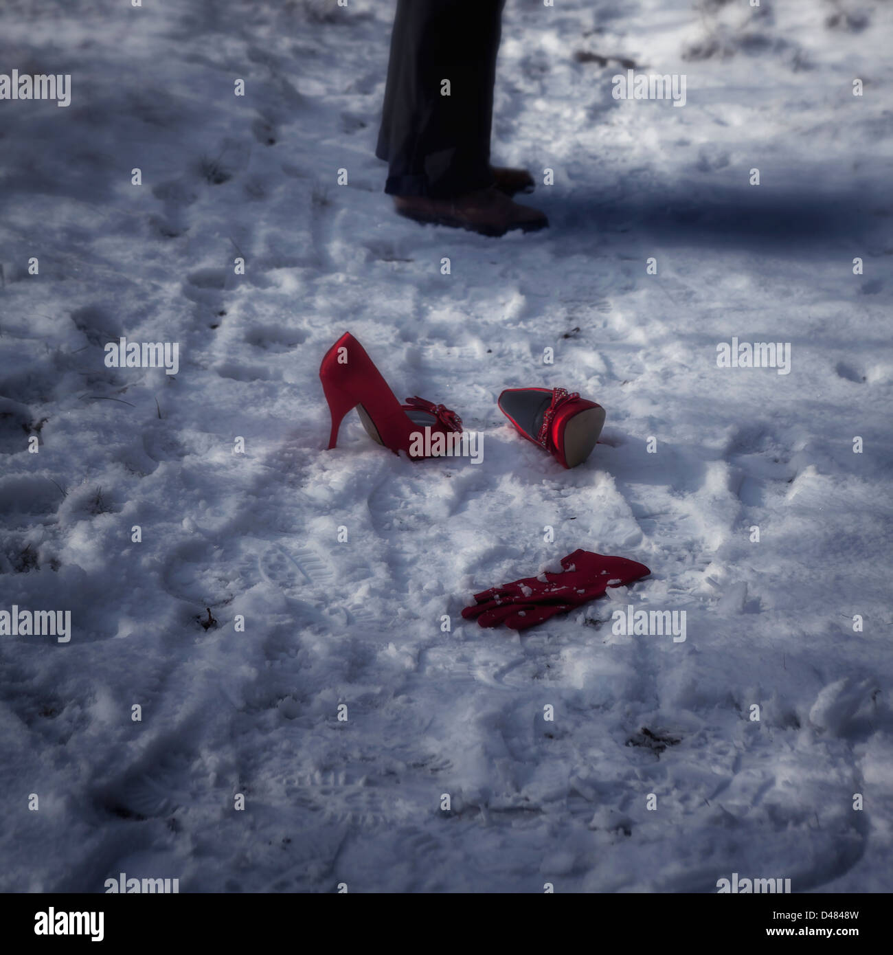 red high heels and a glove in snow, a man is standing beside Stock Photo