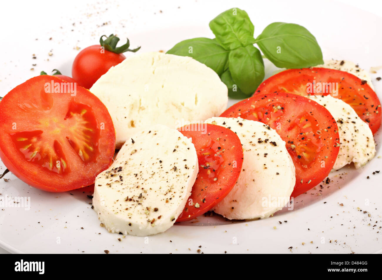 mozzarella and tomato slices with pepper and basilicas. Stock Photo