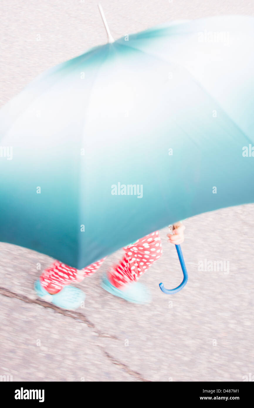 Little girl with dotted pants carrying big umbrella Stock Photo