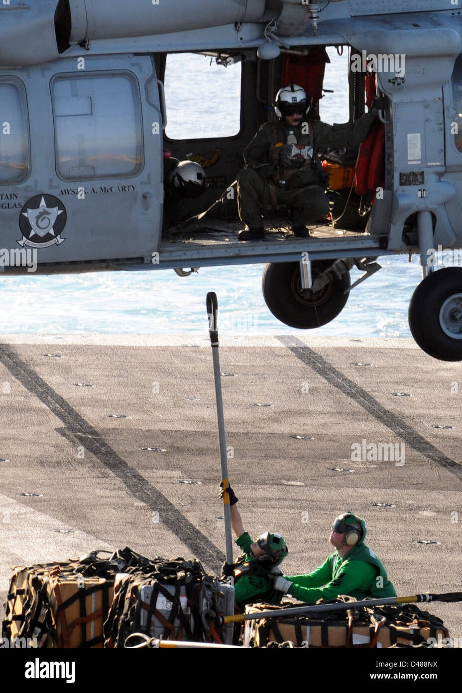 A U.S. Navy sailor secures cargo to an MH-60S helicopter during a ...