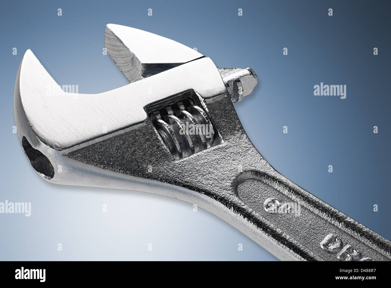 adjustable spanner in front of blue white background Stock Photo