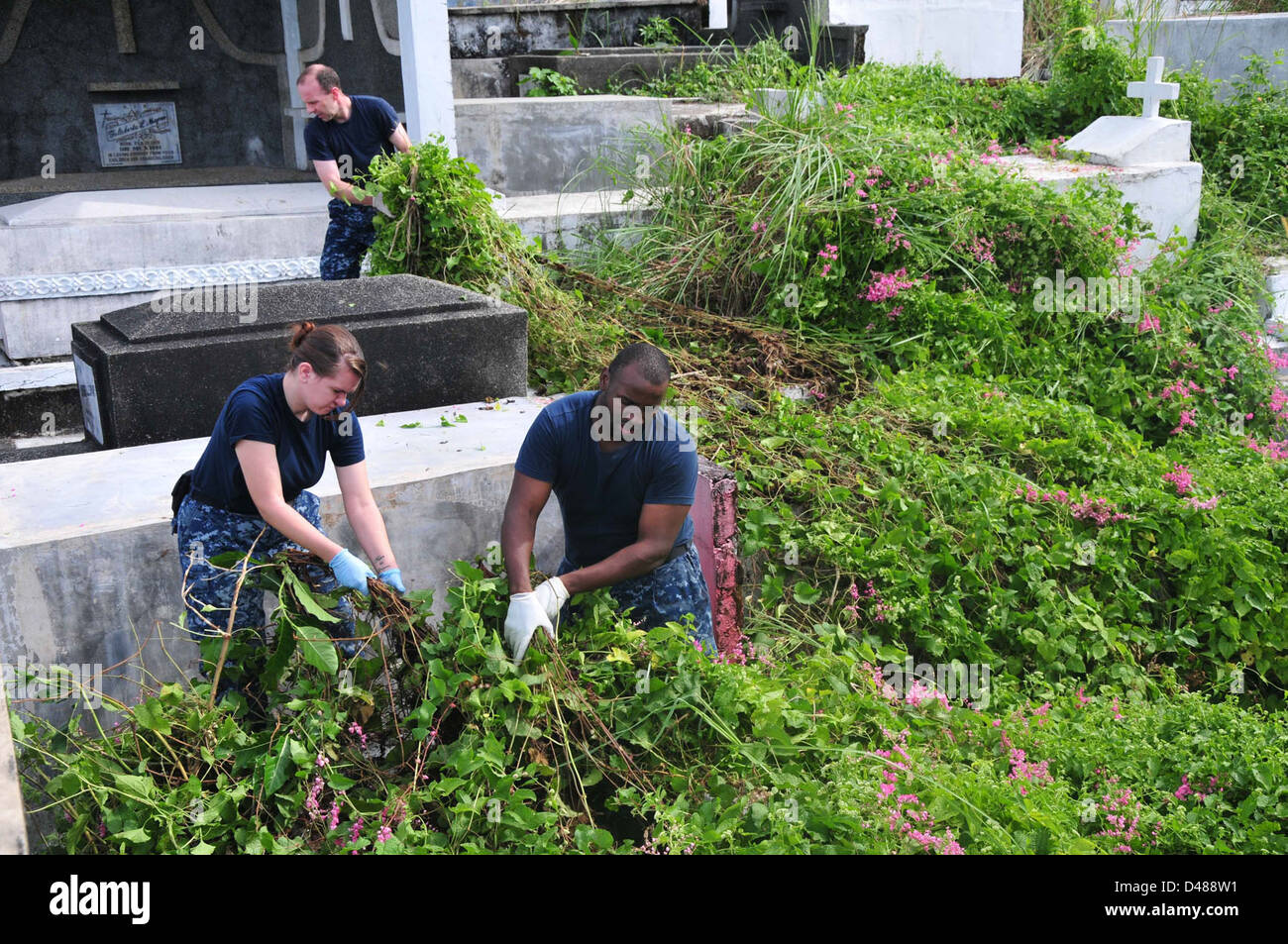 Sailors clear brush from a cemetary in the Philippines. Stock Photo
