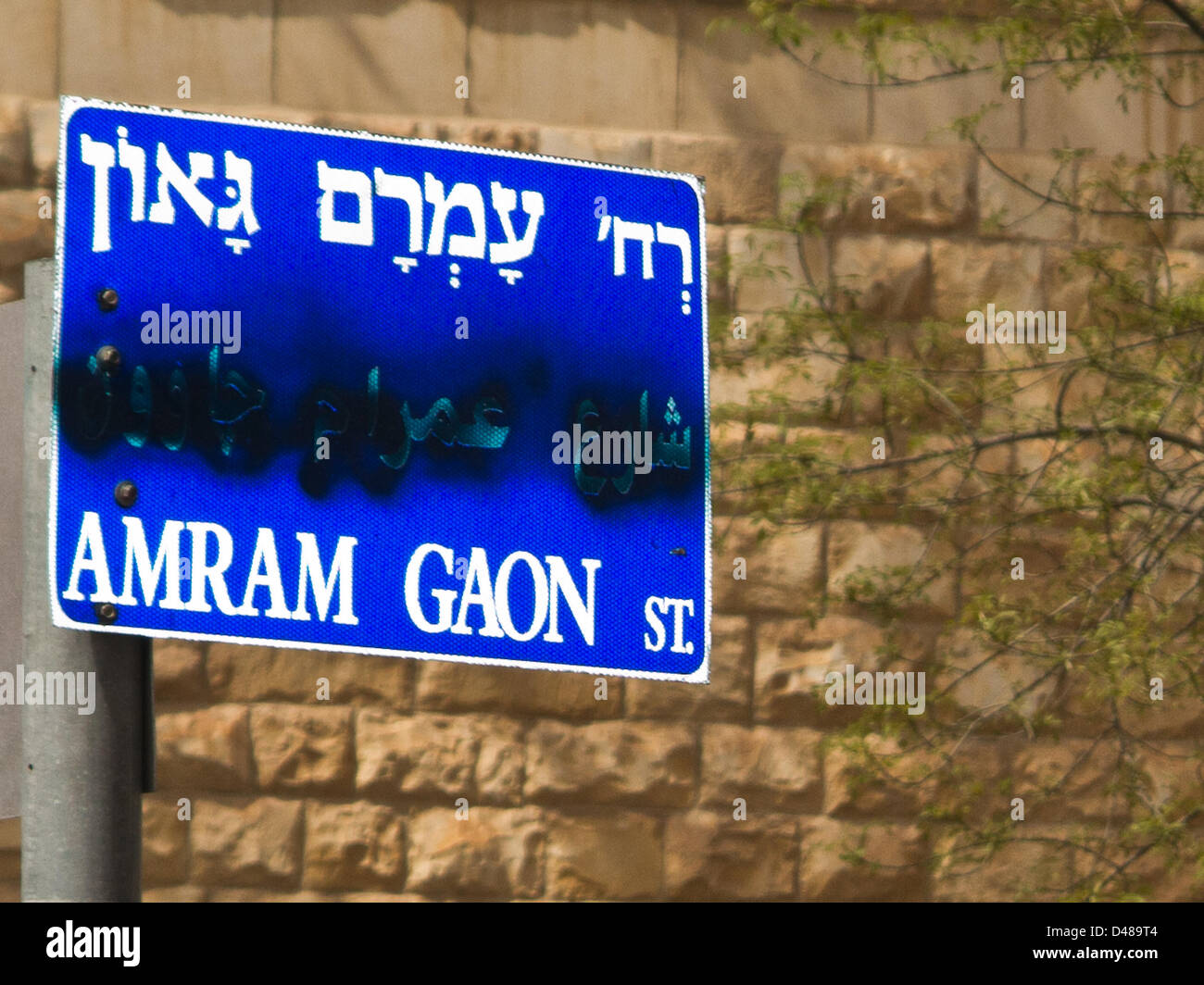 A trilingual sign bearing the name of Amram Gaon Street has been vandalized, marring the Arabic inscription, as part of an ongoing anti-Arab racist campaign, widespread across the Kirayt Moshe neighborhood. Jerusalem, Israel. 8-March-2013.  Signs of anti-Arab racism are evident as a vast number of street signs have been tendentiously vandalized in the modern Zionist-religious neighborhood of Kiryat Moshe, deliberately marring Arabic inscription on trilingual street signs. Stock Photo