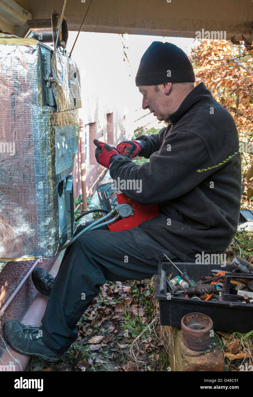 SERVICE ENGINEER SERVICING CENTRAL HEATING OIL-FIRED BOILER IN GARDEN UK, Stock Photo