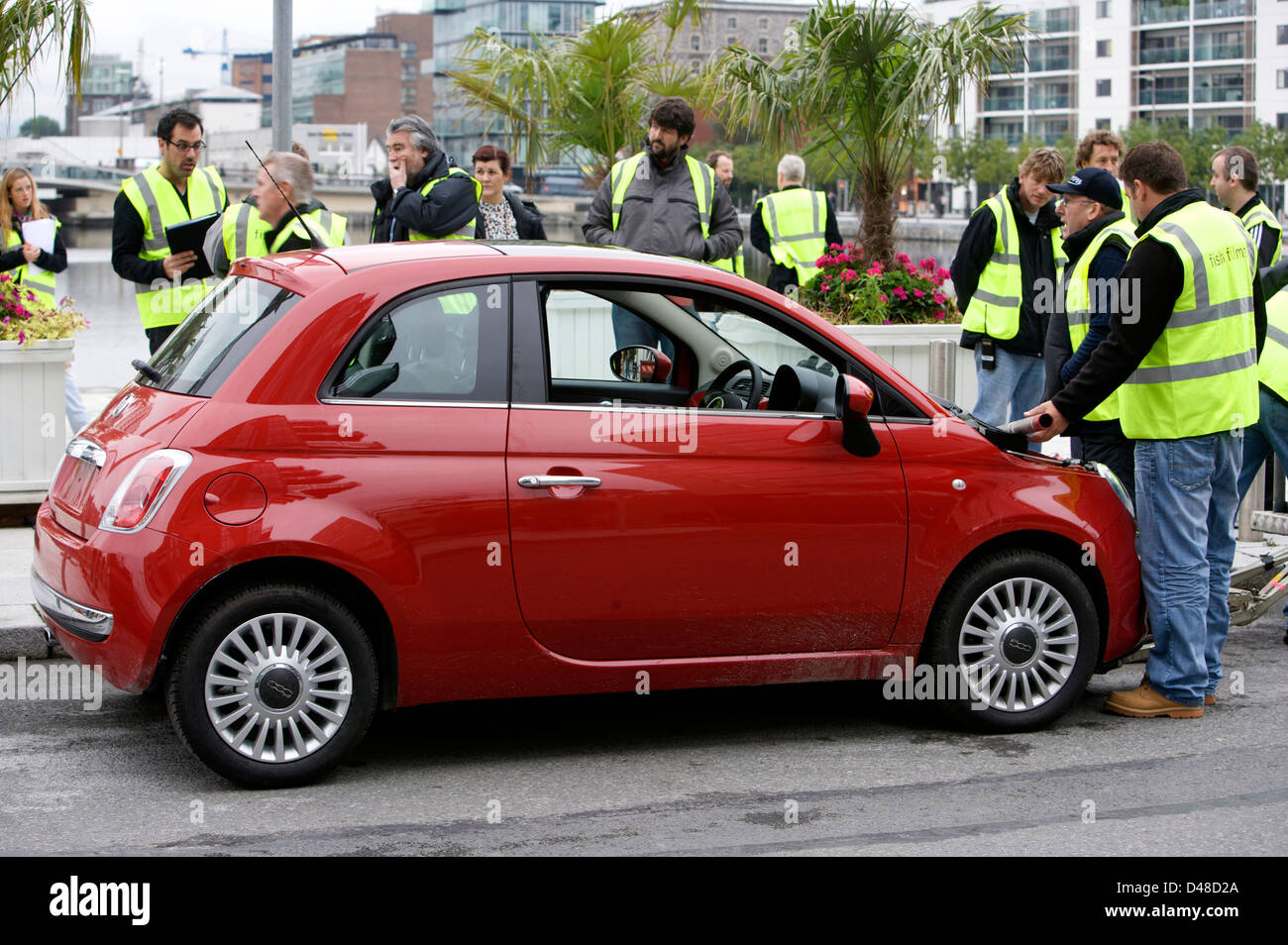 Red Fiat 500 CC with a film rig attached and crew preparing the vehicle Stock Photo