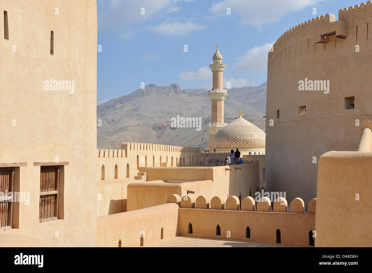The stunning fort with a minaret, a mosque' s dome and stark mountains behind; Nizwa; Al Dakhiliyah, Oman. Stock Photo