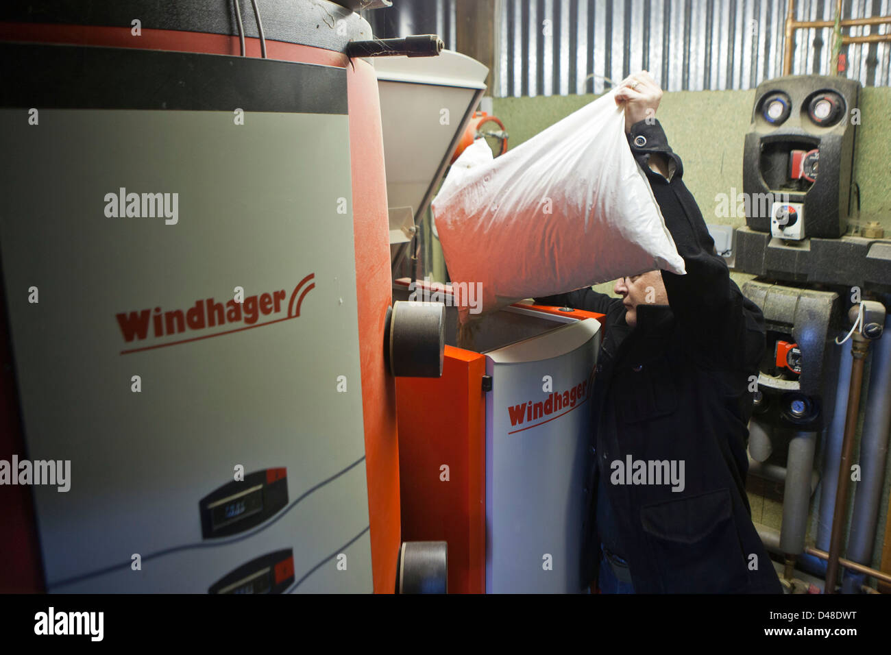 A man refuels a Windhager biomass boiler with wood chip. Llanerchaeron, Wales, UK. Stock Photo