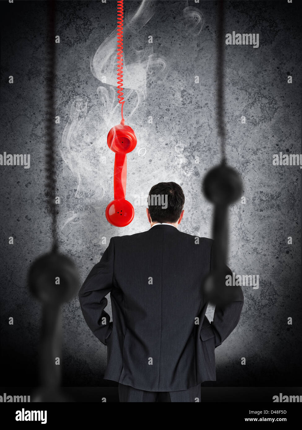 Businessman looking at hanging telephone receiver Stock Photo