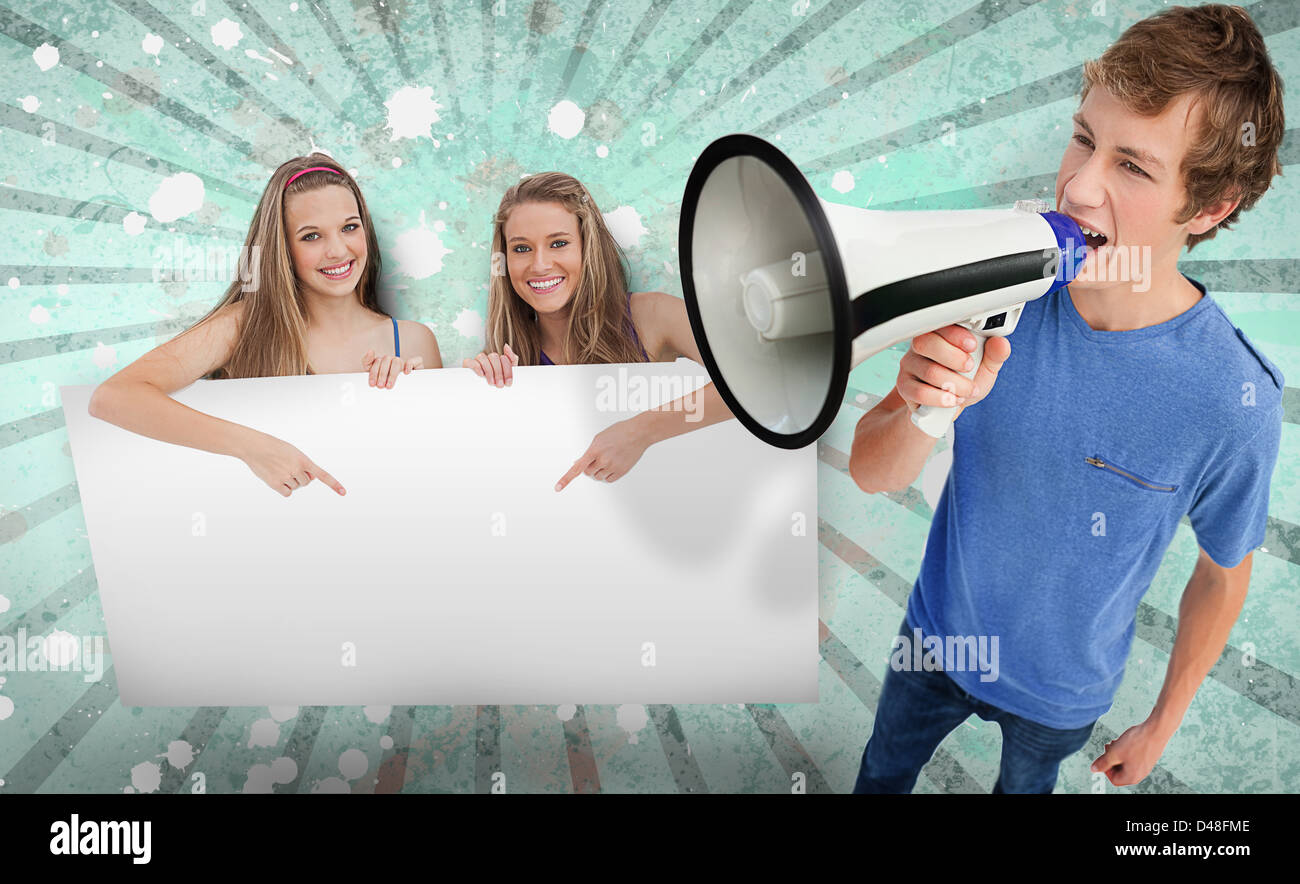 Pretty girls pointing to copy space with young man shouting through megaphone Stock Photo