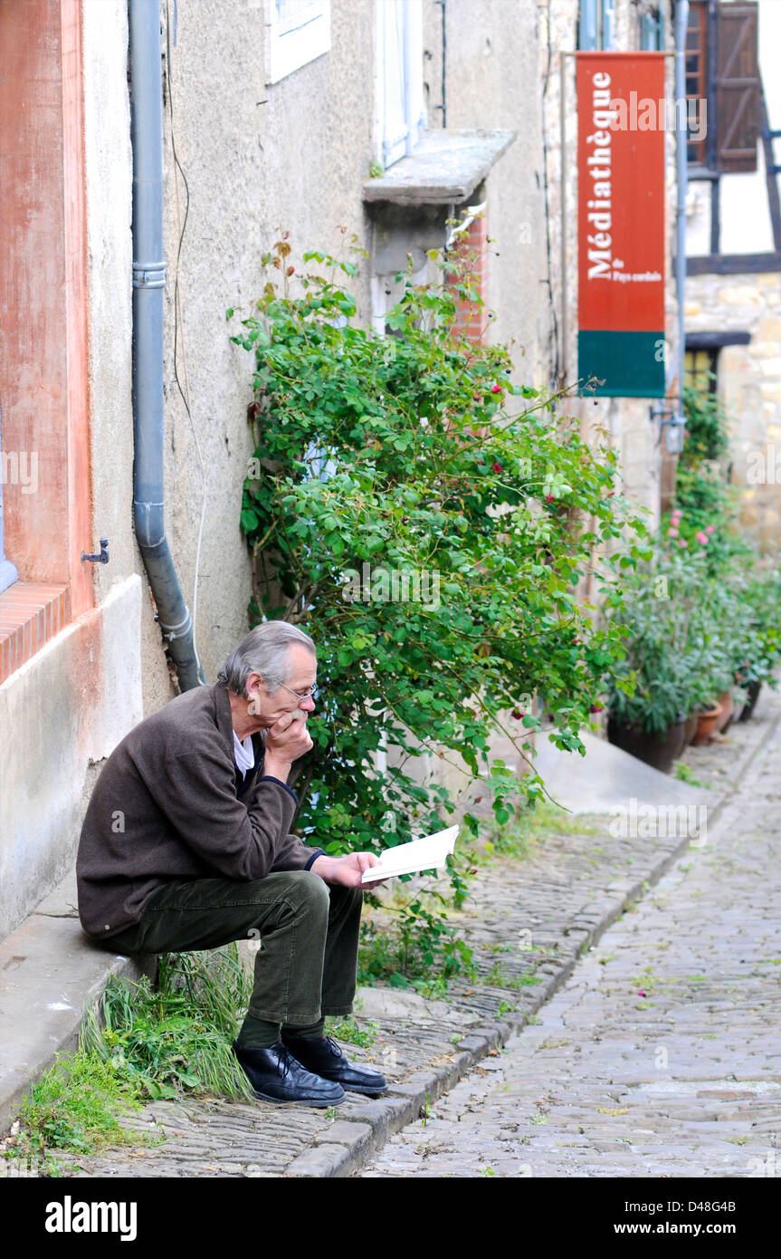 Man reading a book outside more modern media library. Cordes, Tarn, France Stock Photo