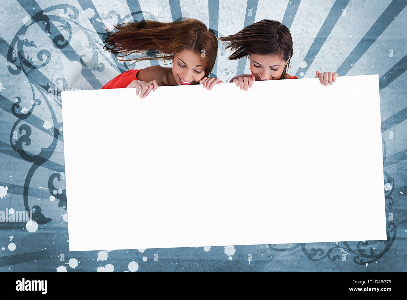 Smiling girls looking down at white copy space screen Stock Photo