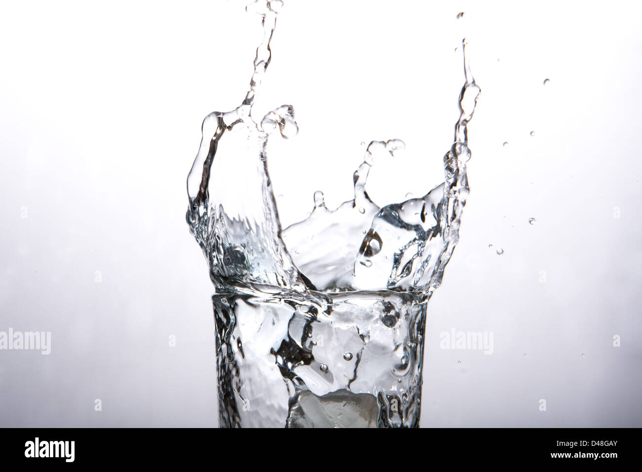 Close up on ice cube falling into glass of water Stock Photo - Alamy