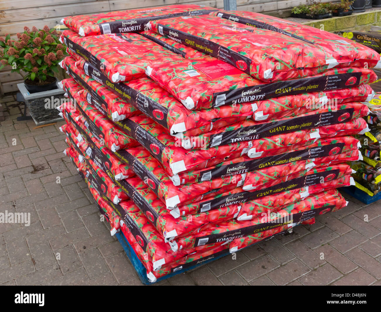 A stack of red grow bags in a garden centre used for growing tomato plants Stock Photo