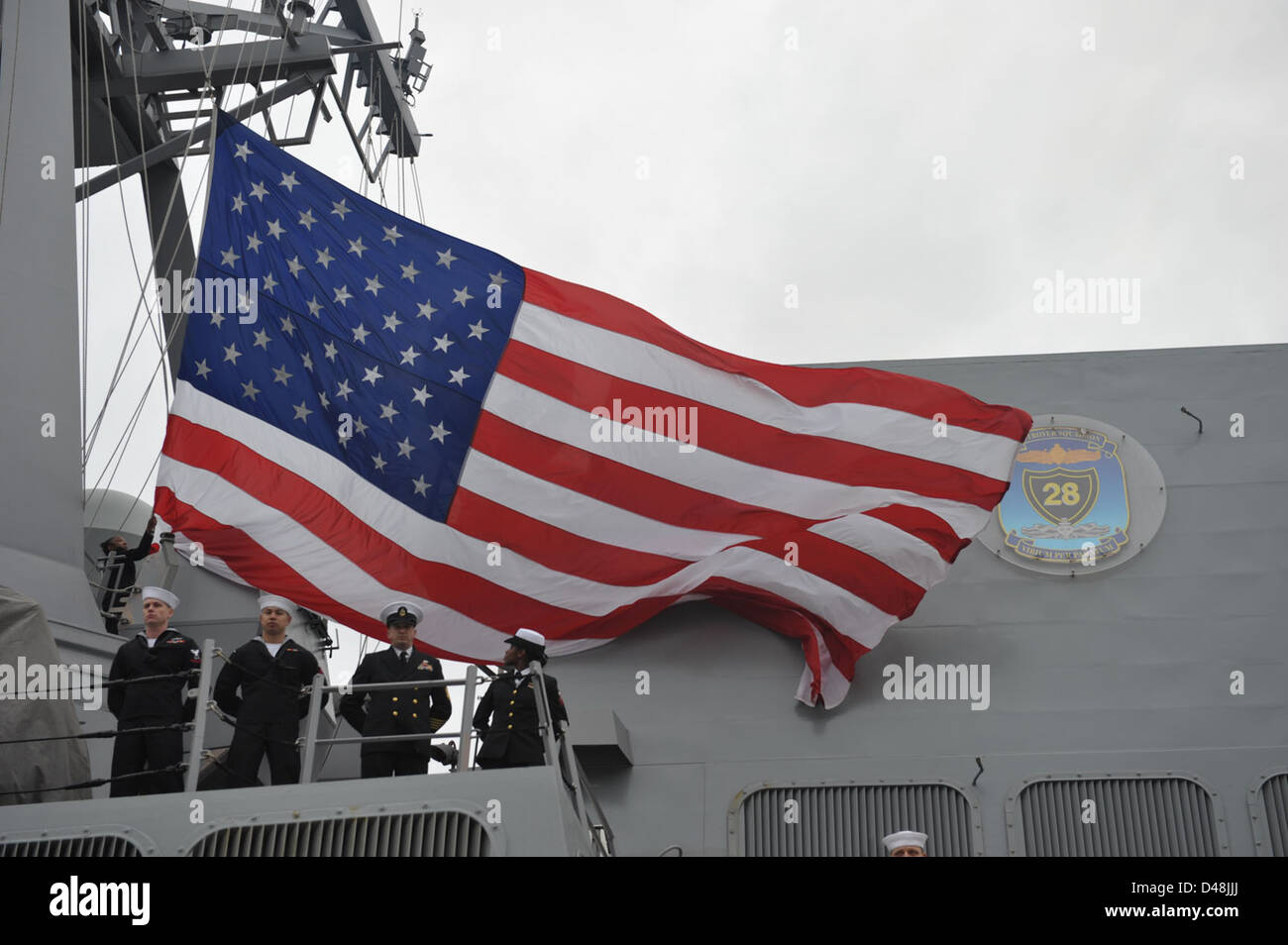 Sailors lower the American flag aboard USS Forrest Sherman. Stock Photo