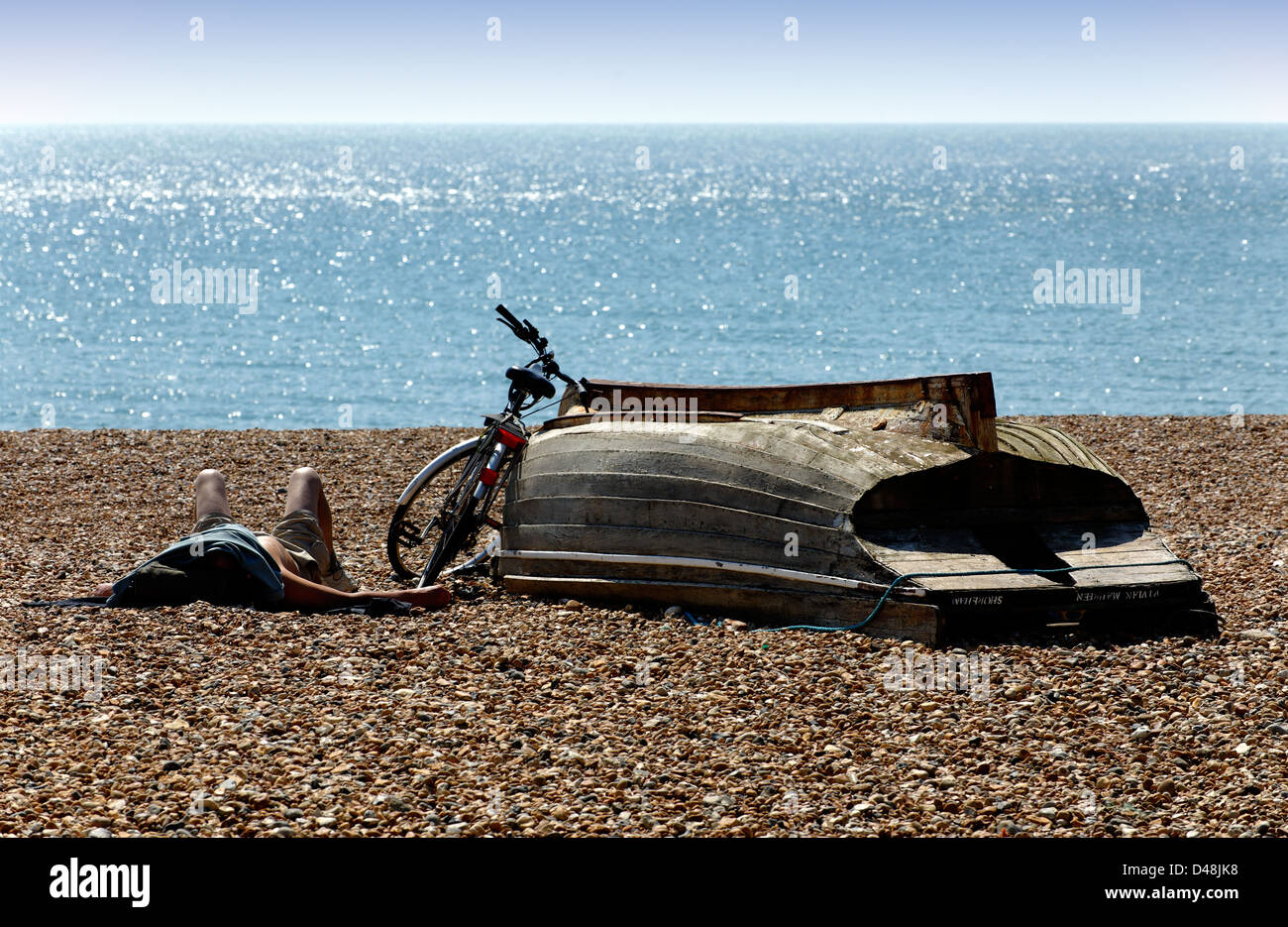 Person sunbathing with head covered on the beach at Hove, East Sussex Stock Photo