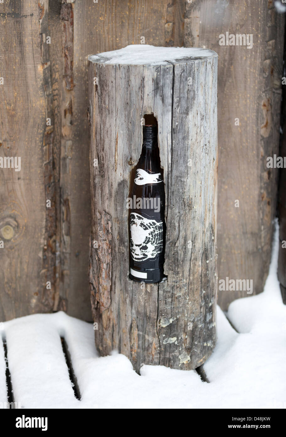 An ingenious wine cooler comprising a log standing in the snow, with a hollow for the bottle Stock Photo