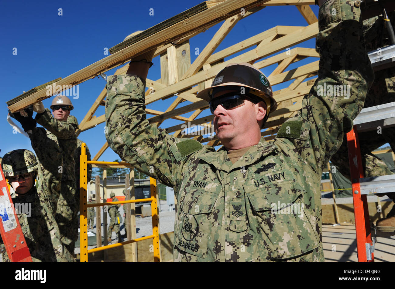 A Seabee holds up an A-frame as a hut is taken down. Stock Photo