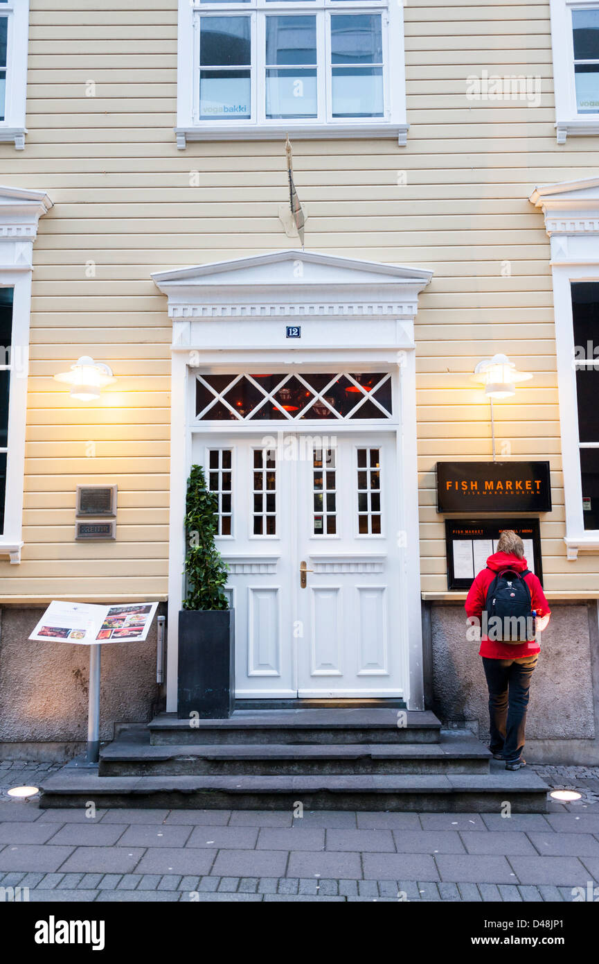 A woman reads the menu at the Fish Market Restaurant Reykjavik Iceland Stock Photo
