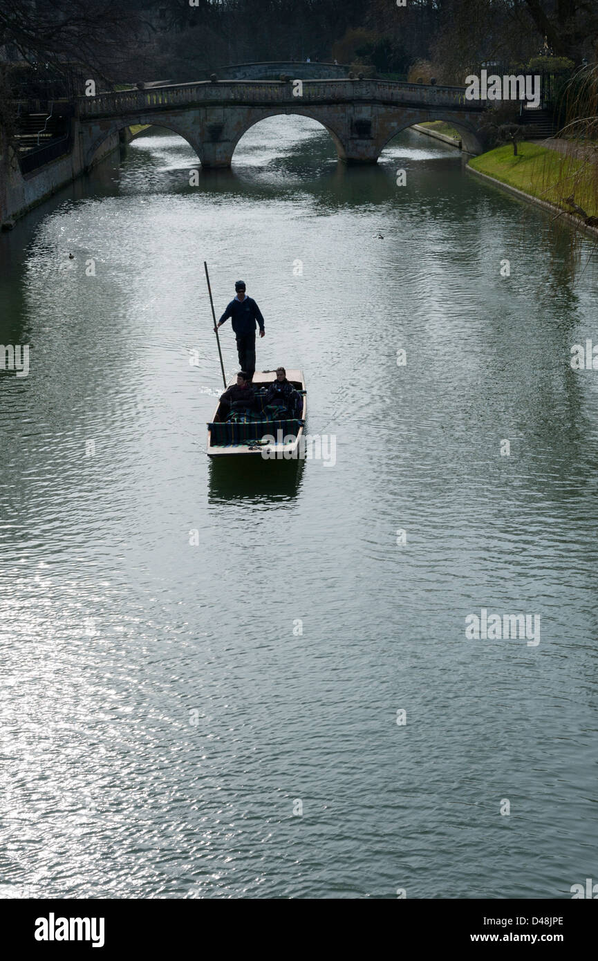 Punting in Cambridge on the River Cam. A punt chauffeur is silhouetted in spring sunshine with Clare Bridge in the background. Stock Photo