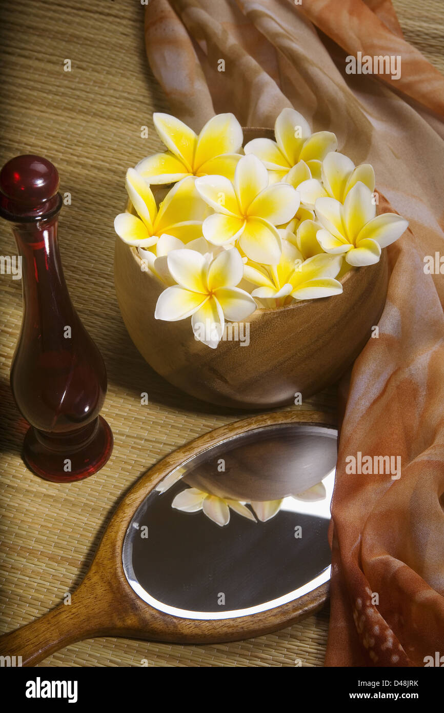 Spa Elements, Bright Yellow Plumerias In A Koa Bowl, Hand Mirror, Scarf, Lauhala Mat And Glass Bottle. Stock Photo