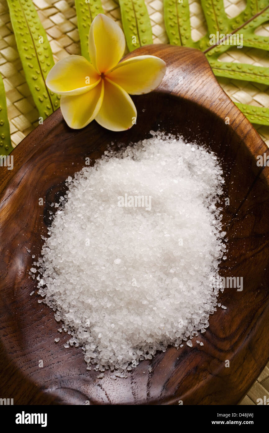 Spa Elements, Koa Bowl Filled With Raw Salt, Garnished With Yellow Plumeria And Leaf On Lauhala Mat. Stock Photo
