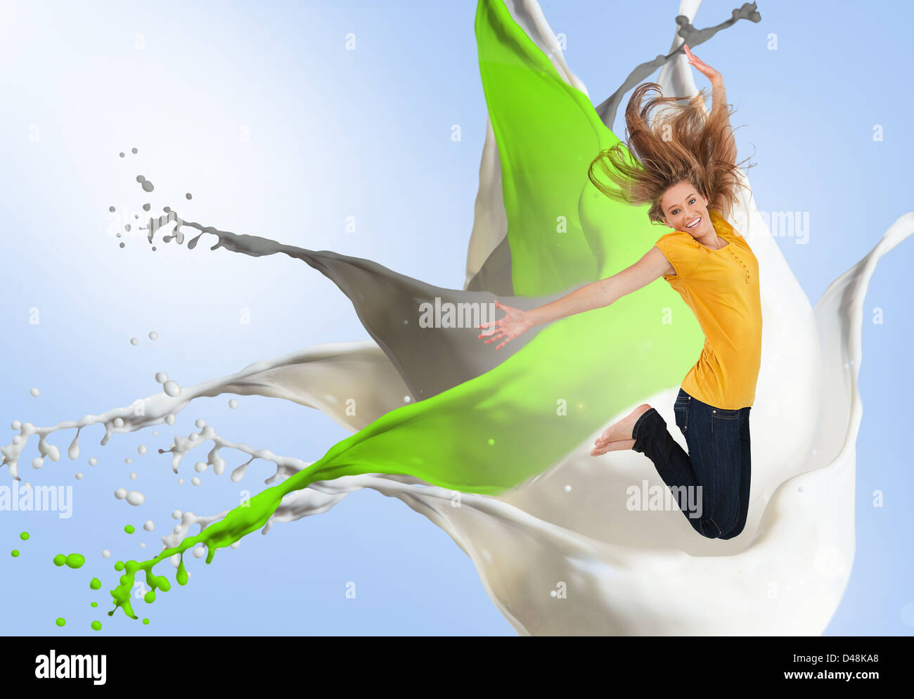Pretty young woman jumping for joy with artistic paint splashes Stock Photo