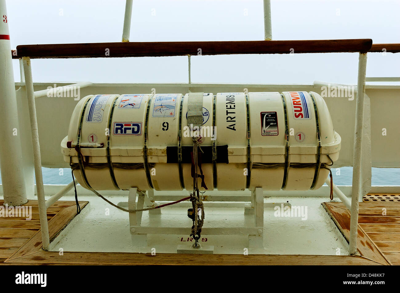 A waterproof cylindrical container containing a SOLAS life raft secured to a steel deck-mounted stowage cradle Stock Photo