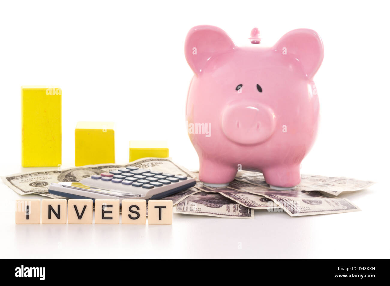 Piggy bank beside graph, calculator and invest spelled out in plastic letter pieces Stock Photo