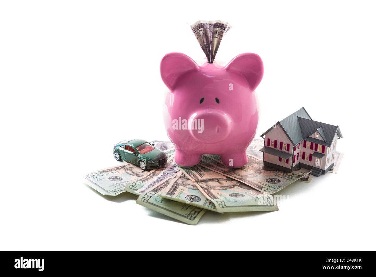 Piggy bank and toy car resting on pile of dollars with mini house Stock Photo