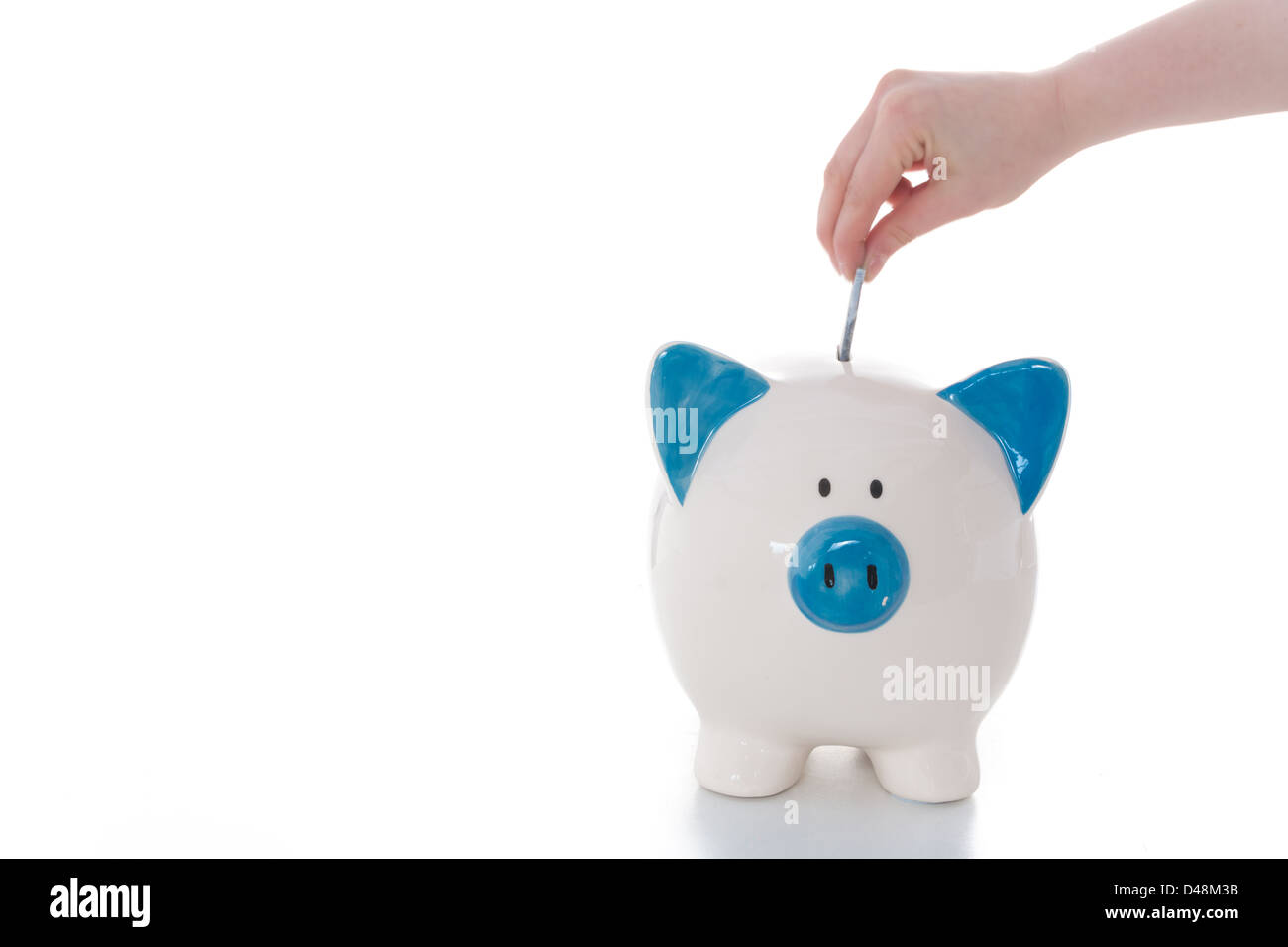 Hand putting money into piggy bank Stock Photo - Alamy