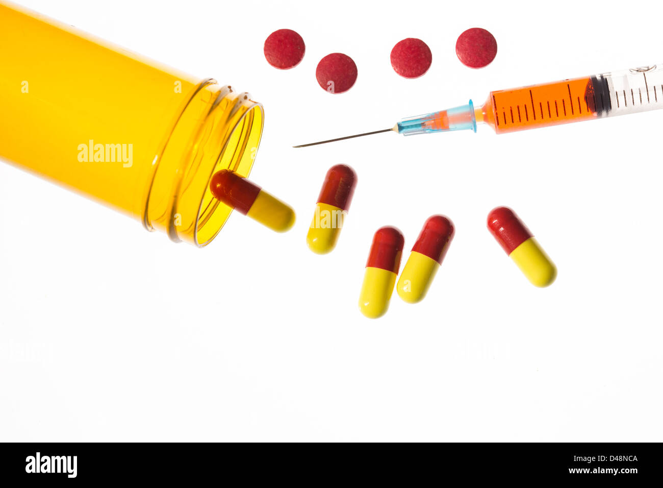 Jar of medicine spilling tablets with syringe Stock Photo